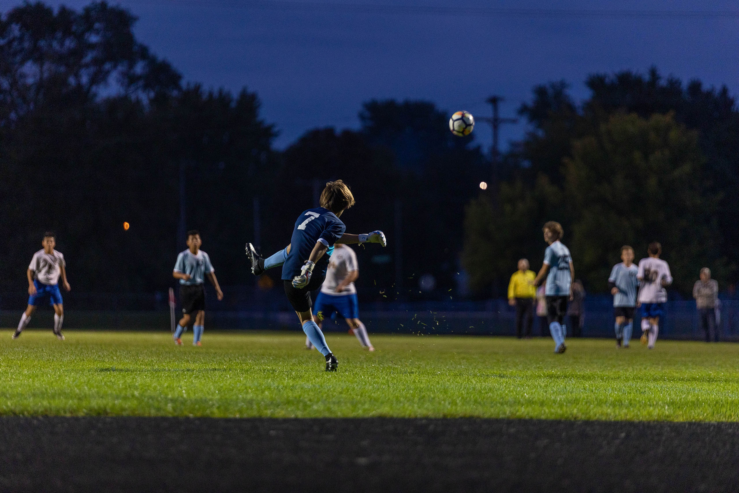 A soccer goalie kicks a soccer ball back into play from the net.